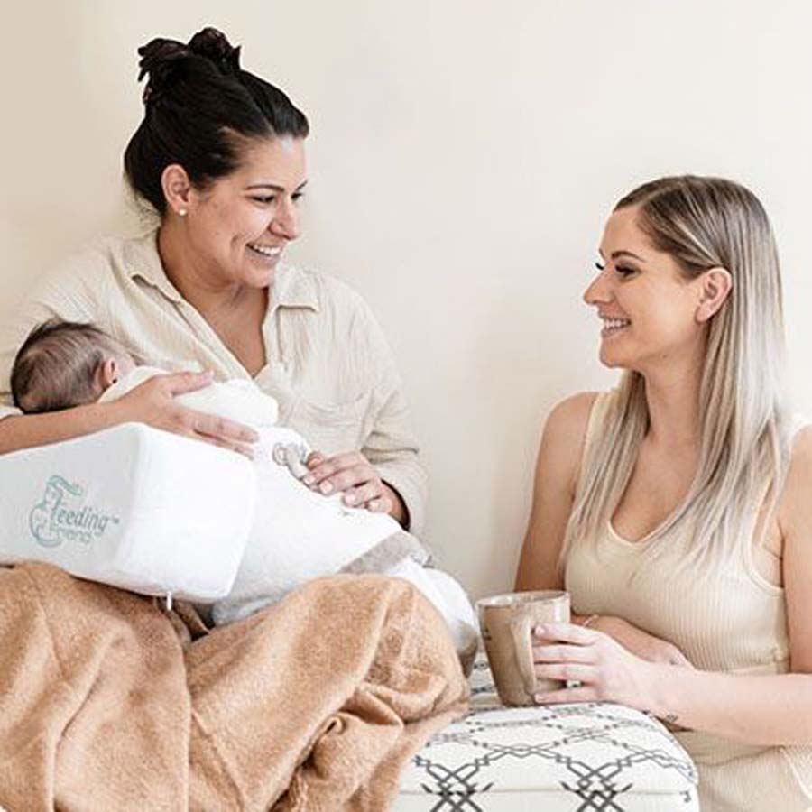 mum using feeding friend to support baby while talking to a friend